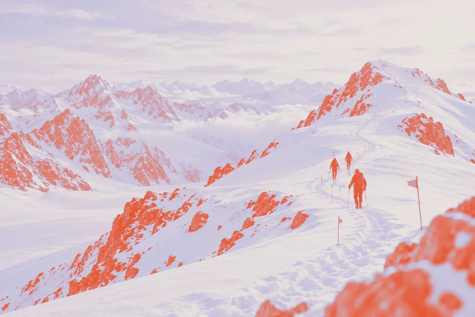 Three climbers following a marked track along a snowy ridge, with route flags spaced along the path.